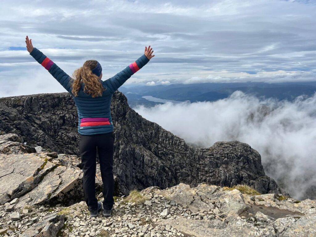 woman with arms raised on mountain